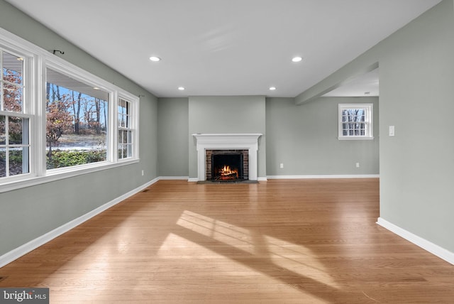 unfurnished living room with plenty of natural light, a fireplace, and light wood-type flooring