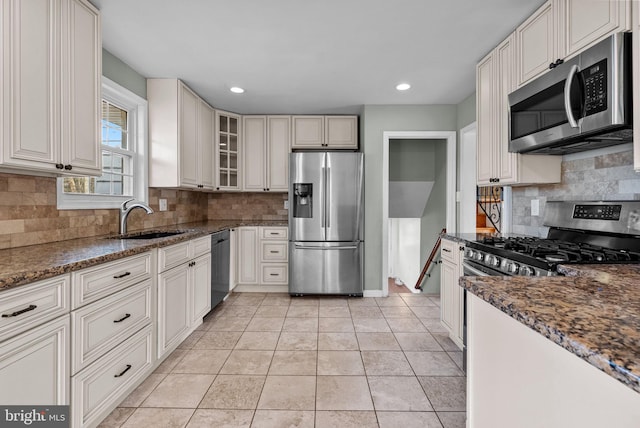 kitchen featuring stainless steel appliances, sink, dark stone countertops, and white cabinets