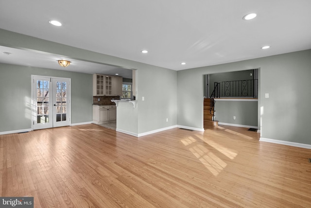 unfurnished living room featuring french doors and light wood-type flooring