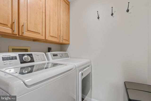 clothes washing area with cabinets and washer and dryer