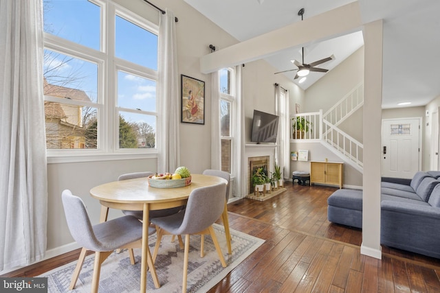 dining area with dark hardwood / wood-style flooring, ceiling fan, high vaulted ceiling, and a healthy amount of sunlight