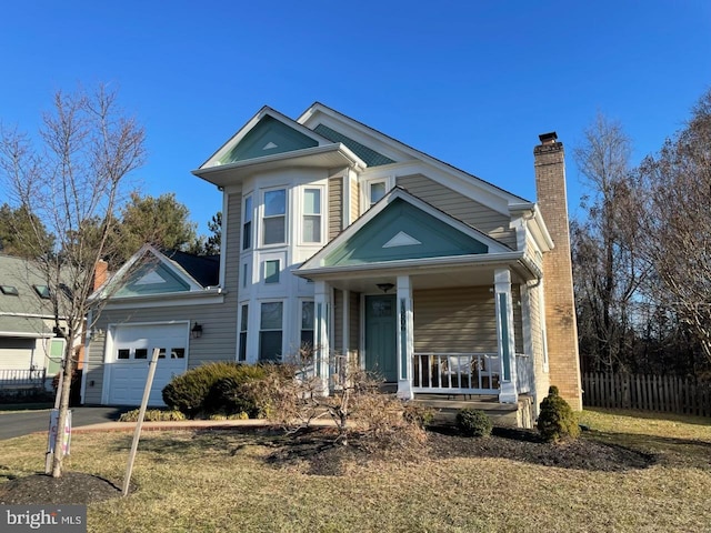 view of front of property featuring a porch, a garage, and a front yard