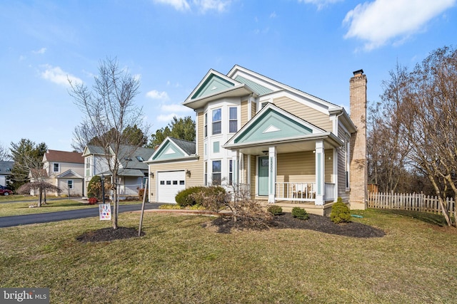 view of front of home with a garage, covered porch, and a front lawn