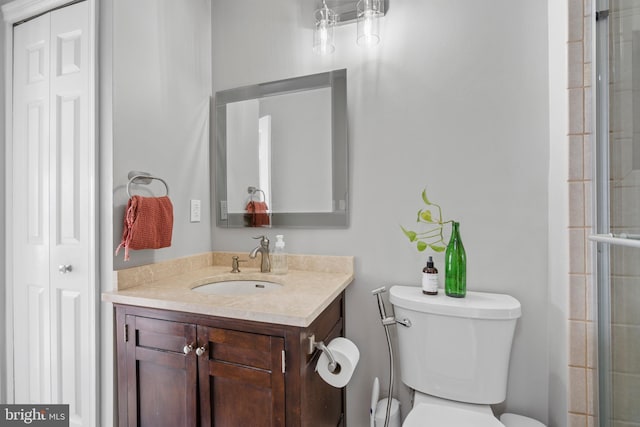 bathroom featuring vanity, an enclosed shower, and toilet