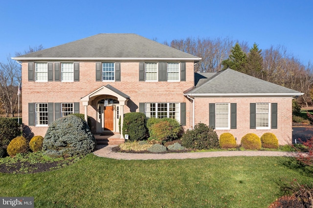 colonial-style house featuring a front lawn