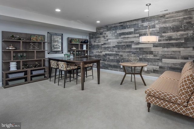 dining area with light colored carpet and wood walls