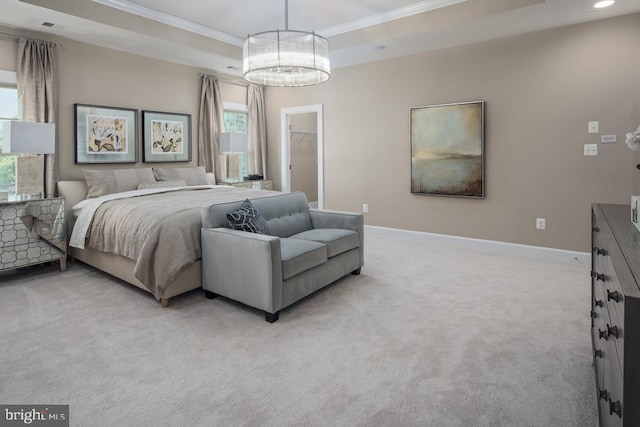 carpeted bedroom featuring a closet, a walk in closet, ornamental molding, and a raised ceiling