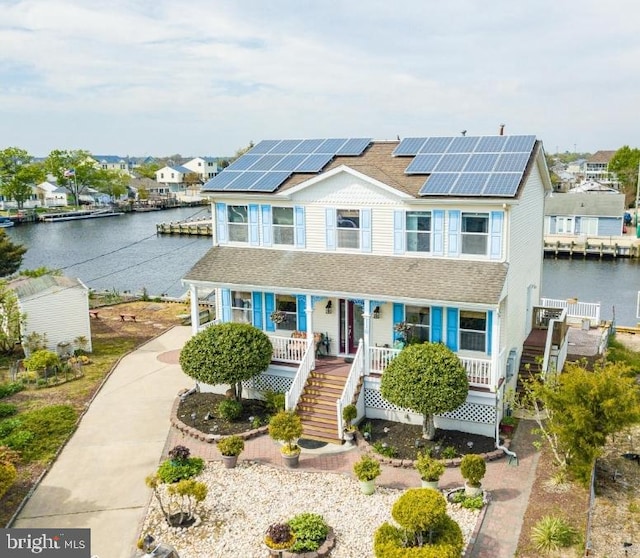 view of front facade with a porch, a water view, and solar panels