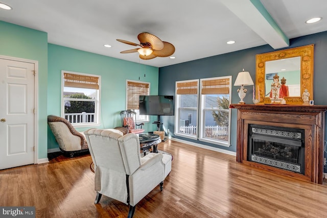 living room with hardwood / wood-style flooring, ceiling fan, and beam ceiling