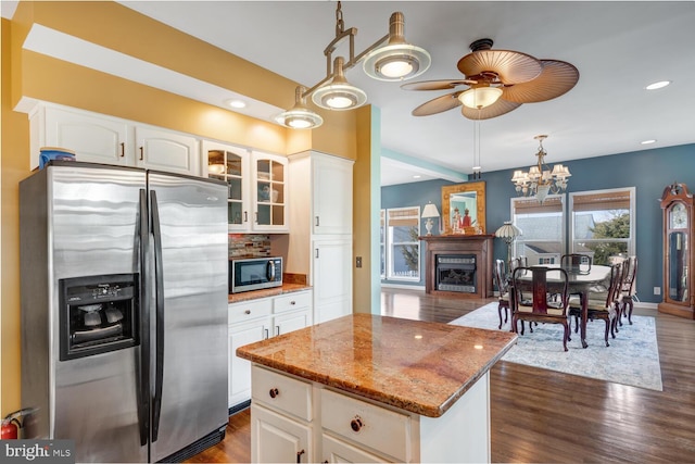 kitchen with a kitchen island, dark hardwood / wood-style floors, white cabinetry, stainless steel appliances, and light stone countertops