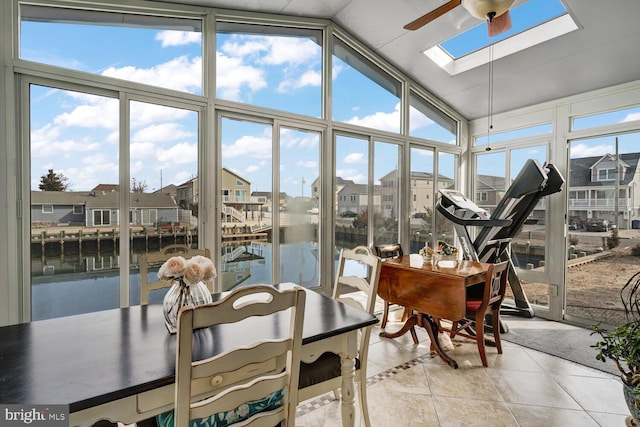 sunroom with vaulted ceiling with skylight, ceiling fan, and a water view