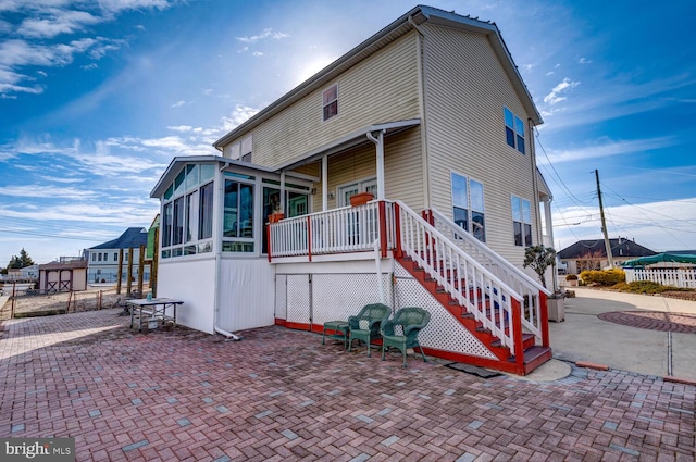 view of side of property with a sunroom and a patio area