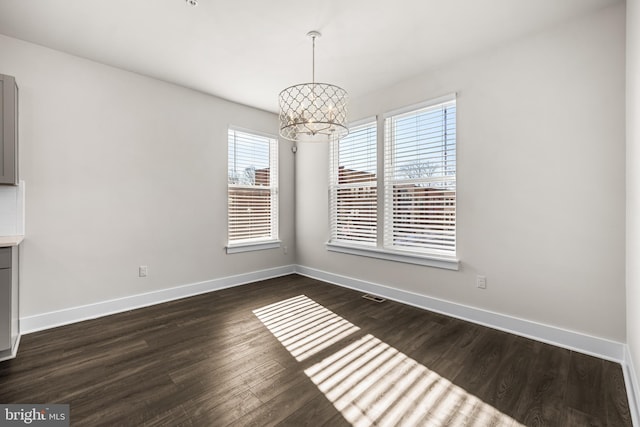 unfurnished dining area with an inviting chandelier and dark hardwood / wood-style floors