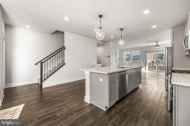 kitchen featuring sink, gray cabinetry, decorative light fixtures, appliances with stainless steel finishes, and an island with sink