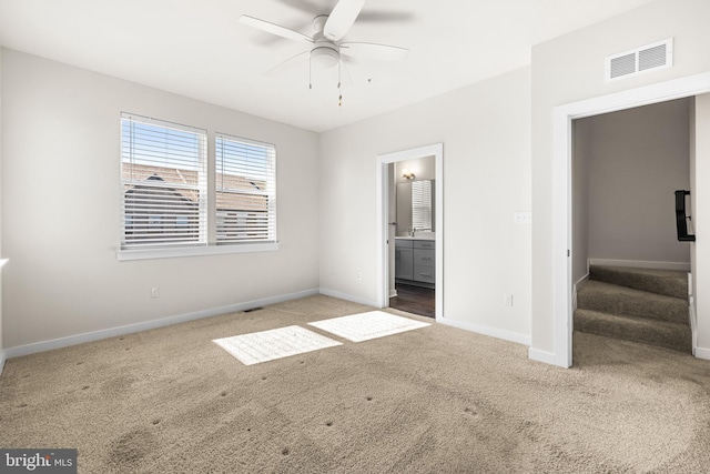 unfurnished bedroom with ceiling fan, ensuite bathroom, and carpet floors