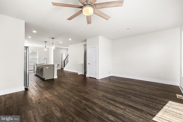 unfurnished living room featuring ceiling fan and dark hardwood / wood-style flooring