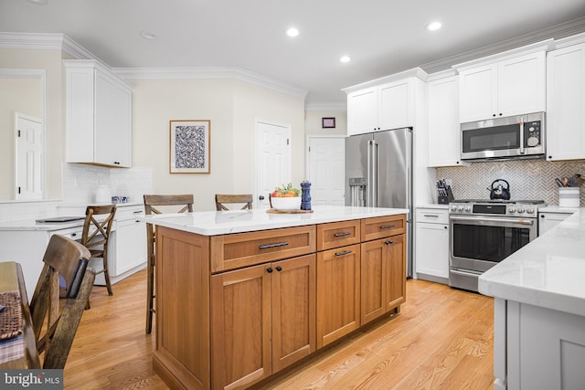 kitchen featuring a kitchen island, white cabinetry, ornamental molding, light stone counters, and stainless steel appliances