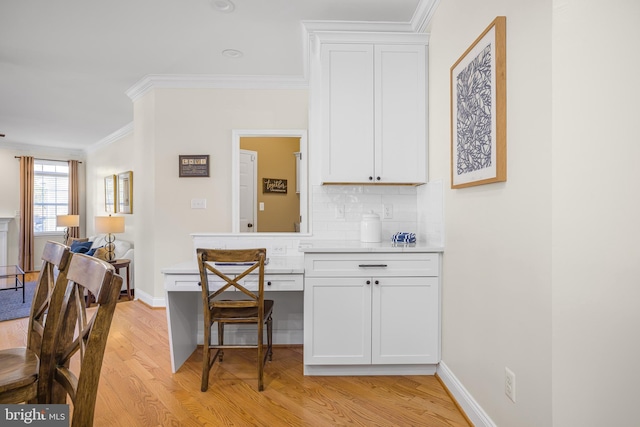 kitchen featuring white cabinetry, ornamental molding, decorative backsplash, and light wood-type flooring