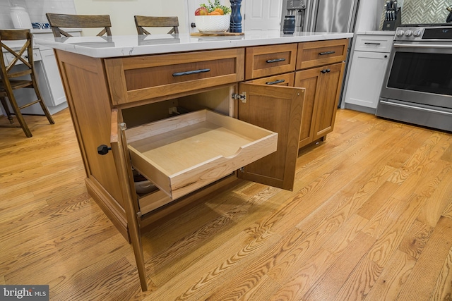 room details featuring tasteful backsplash, a center island, stainless steel range with electric cooktop, and light hardwood / wood-style flooring