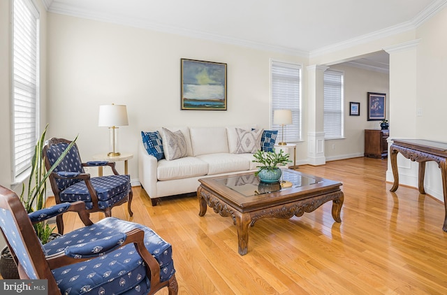 living room featuring crown molding, decorative columns, and light hardwood / wood-style floors