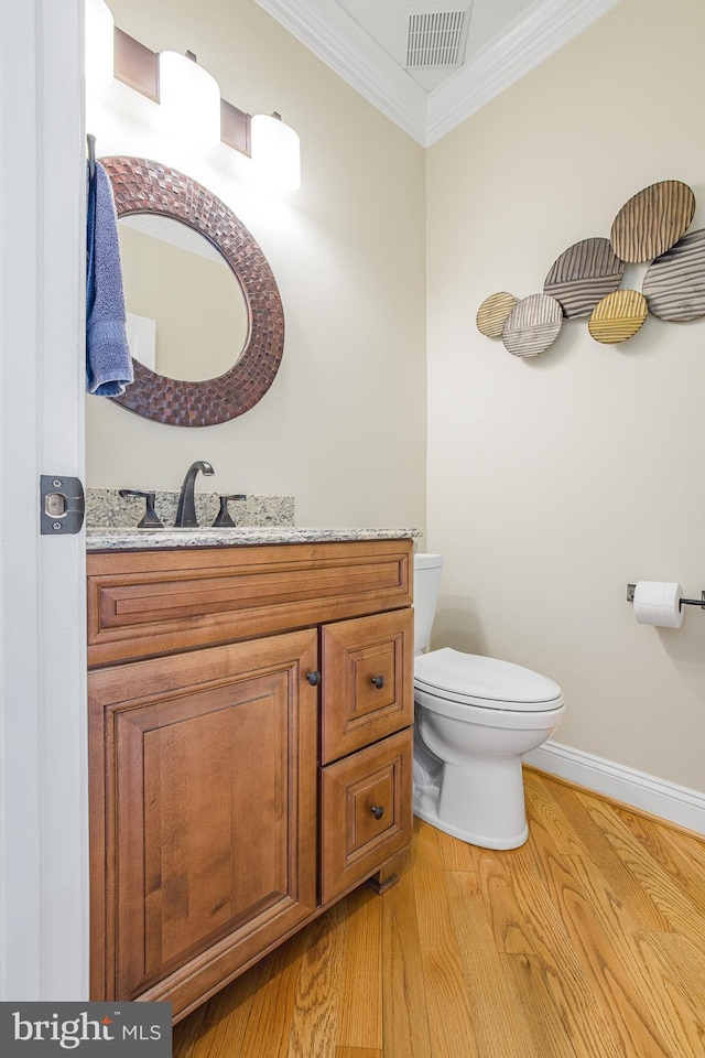 bathroom featuring ornamental molding, toilet, wood-type flooring, and vanity