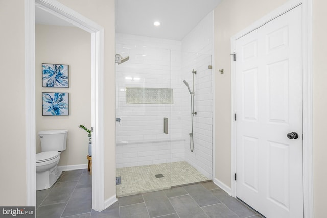 bathroom with toilet, a shower with shower door, and tile patterned flooring