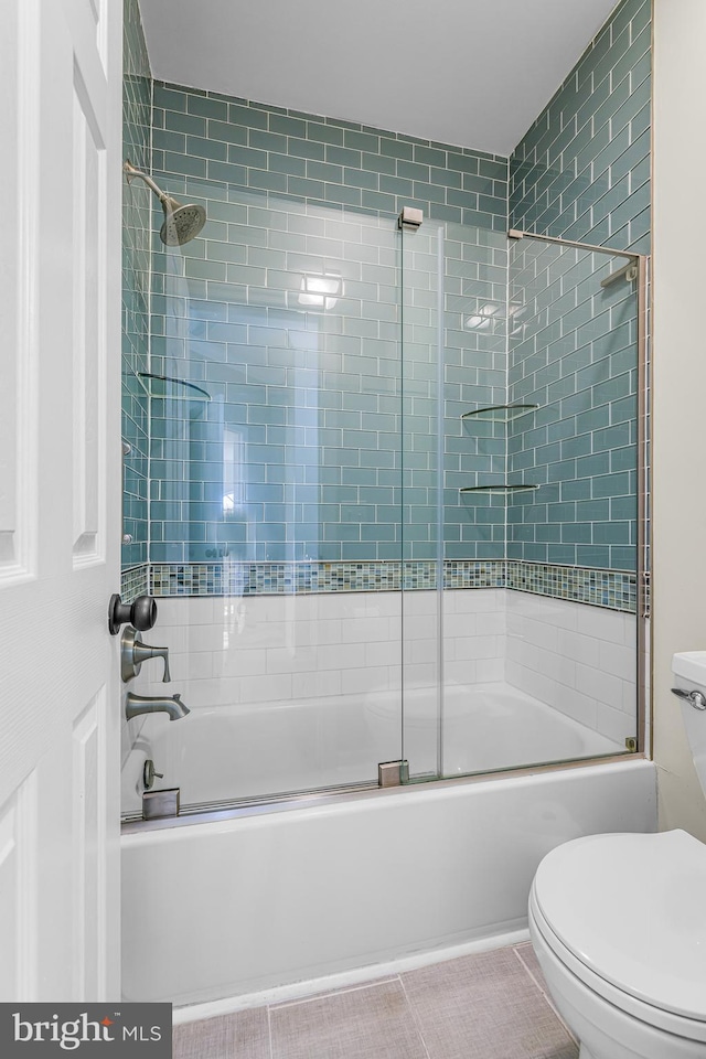 bathroom featuring tile patterned floors, toilet, and combined bath / shower with glass door