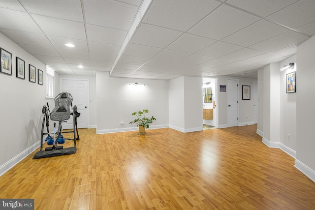 exercise room featuring a drop ceiling and light hardwood / wood-style floors