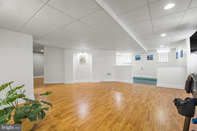 interior space with a drop ceiling and wood-type flooring