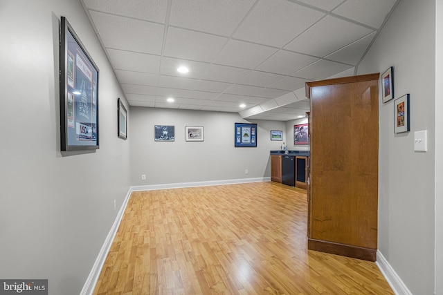 basement featuring a drop ceiling and light wood-type flooring