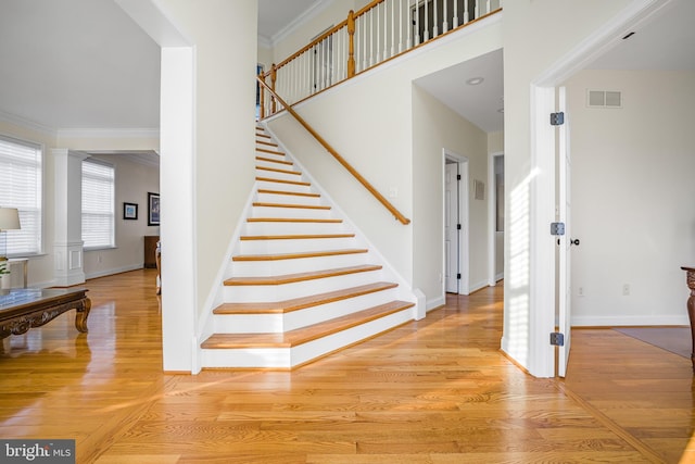 staircase with hardwood / wood-style floors, ornamental molding, and a high ceiling