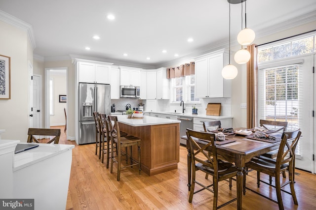 kitchen with stainless steel appliances, white cabinetry, hanging light fixtures, and a kitchen island