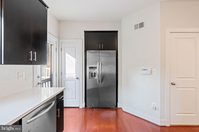 kitchen featuring dark wood-type flooring, appliances with stainless steel finishes, and decorative backsplash