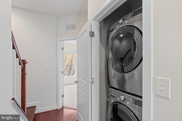 laundry room with stacked washer and dryer and dark hardwood / wood-style flooring