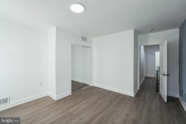 unfurnished bedroom with dark hardwood / wood-style flooring and a closet