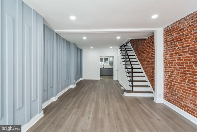 interior space with hardwood / wood-style floors and brick wall