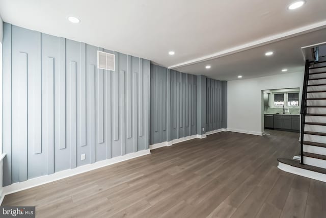 basement with dark hardwood / wood-style flooring and sink