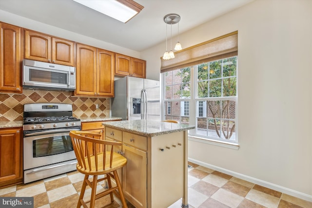 kitchen featuring a kitchen island, pendant lighting, stainless steel appliances, light stone countertops, and backsplash