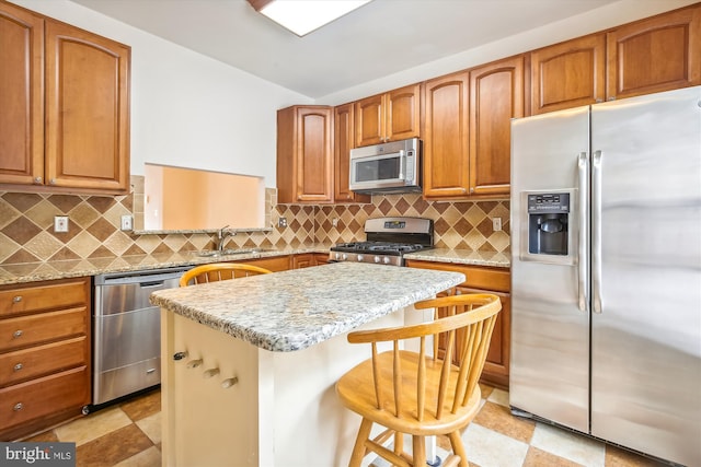 kitchen with light stone counters, appliances with stainless steel finishes, a breakfast bar, and sink