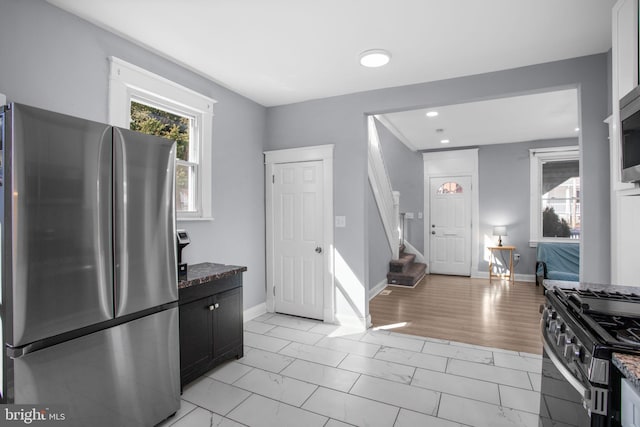 kitchen featuring dark stone counters, baseboards, marble finish floor, and appliances with stainless steel finishes