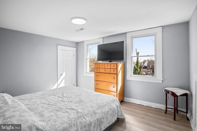 bedroom with visible vents, multiple windows, baseboards, and wood finished floors