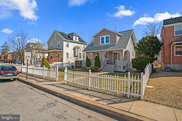 view of front of home featuring a fenced front yard, a residential view, a porch, and a shingled roof