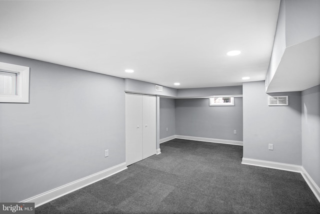 below grade area featuring visible vents, recessed lighting, baseboards, and dark colored carpet