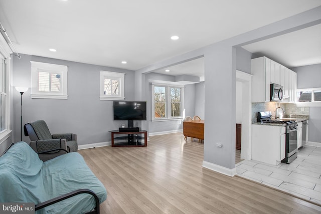 living area featuring light wood-style flooring, plenty of natural light, and baseboards