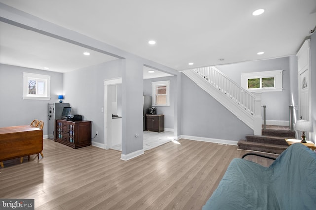 living room with a wealth of natural light, light wood-style flooring, and stairs