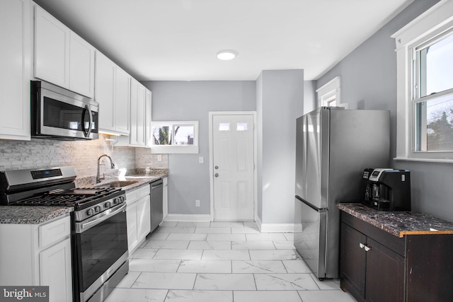 kitchen with marble finish floor, a sink, stainless steel appliances, white cabinets, and a healthy amount of sunlight