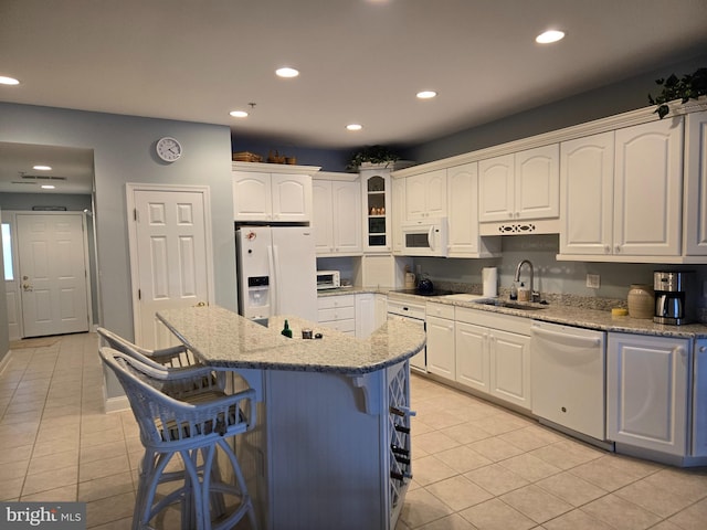 kitchen featuring white cabinets, white appliances, a kitchen breakfast bar, and a sink