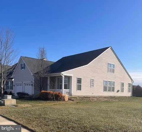 view of side of property featuring an attached garage and a lawn