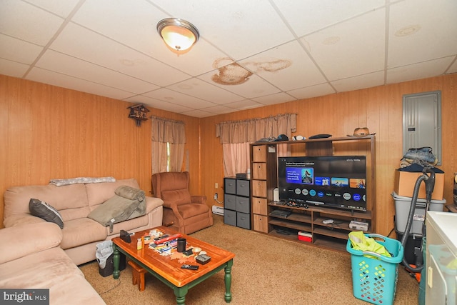 carpeted living room featuring a drop ceiling, a baseboard heating unit, and electric panel