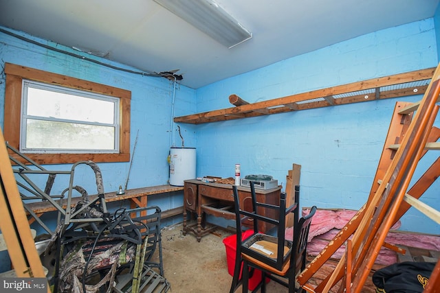 miscellaneous room featuring a workshop area, concrete flooring, and water heater